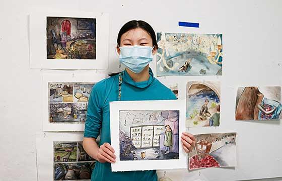 Ting standing in studio, mask on, 拿着一幅小画，背景是挂在墙上的其他画