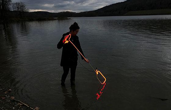 woman stands in lake at dusk with hot glass or neon. time lapse