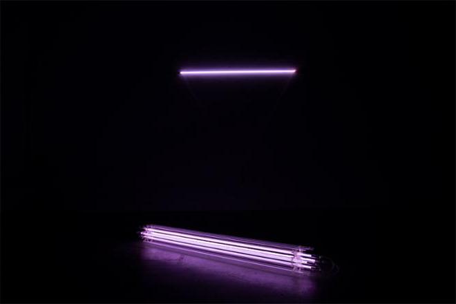 Install view of ——————— and ============. ============ is placed on a  polished concrete floor, reflecting a violet light within the darkened room.     
