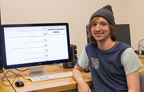 Sam Schultheis posing with computer and work. 