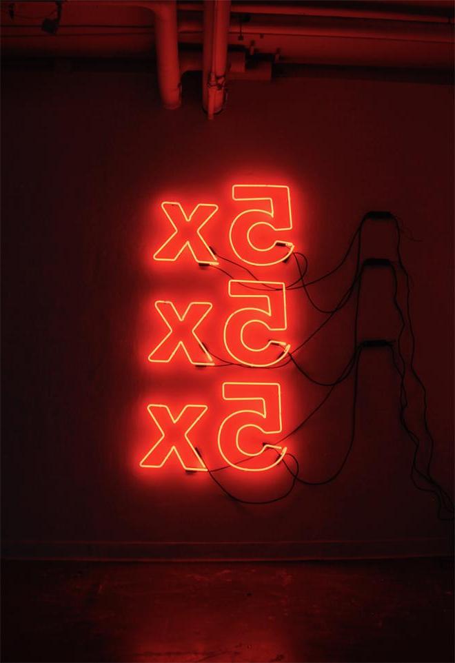 垂直墙上安装了三个橙色霓虹灯标志，拼写为“5x”，堆叠在一起.